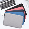 A stack of colorful laptop sleeves and a silver laptop are displayed on a white surface.