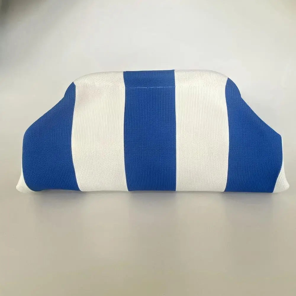Clutch con rayas verticales azules y blancas sobre fondo gris claro.