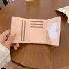 Cartera de cuero PU rosa claro plegable abierta sobre una mesa de madera.
