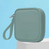 Bolsa portátil multifuncional de almacenamiento para auriculares de color verde claro con cremallera, mostrada sobre una supe
