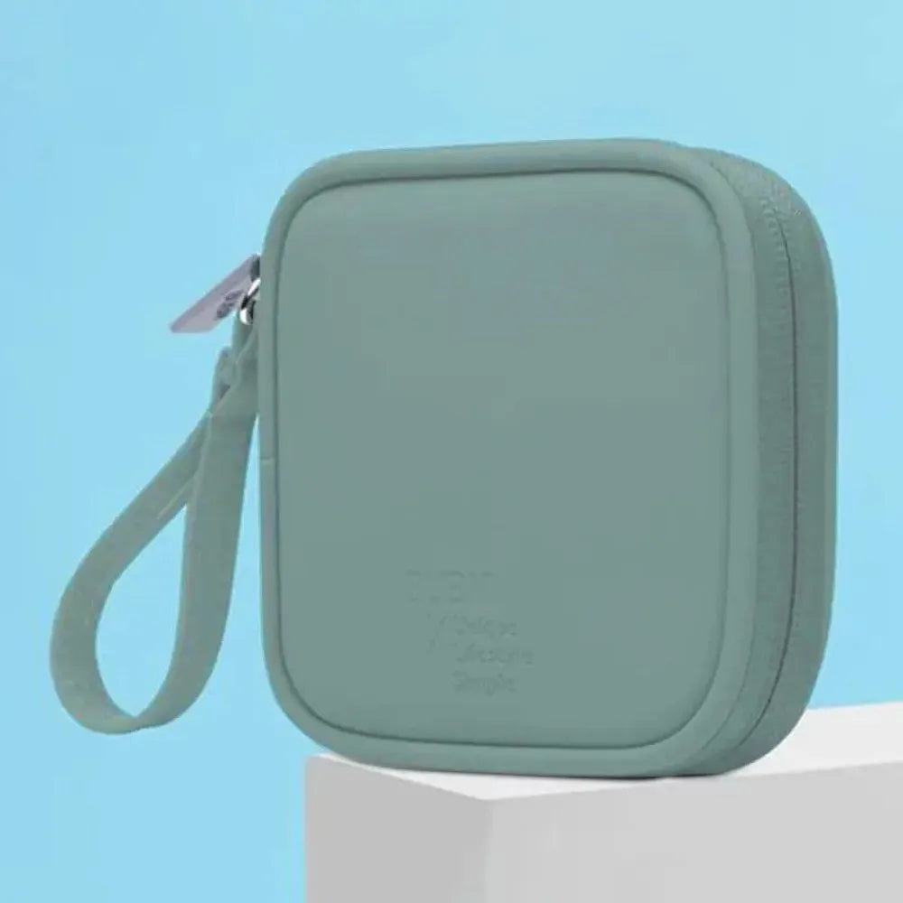 Bolsa portátil multifuncional de almacenamiento para auriculares de color verde claro con cremallera, mostrada sobre una supe