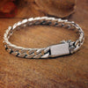 Sterling silver punk charm bracelet featuring a chain design and a padlock clasp resting on a wooden surface.