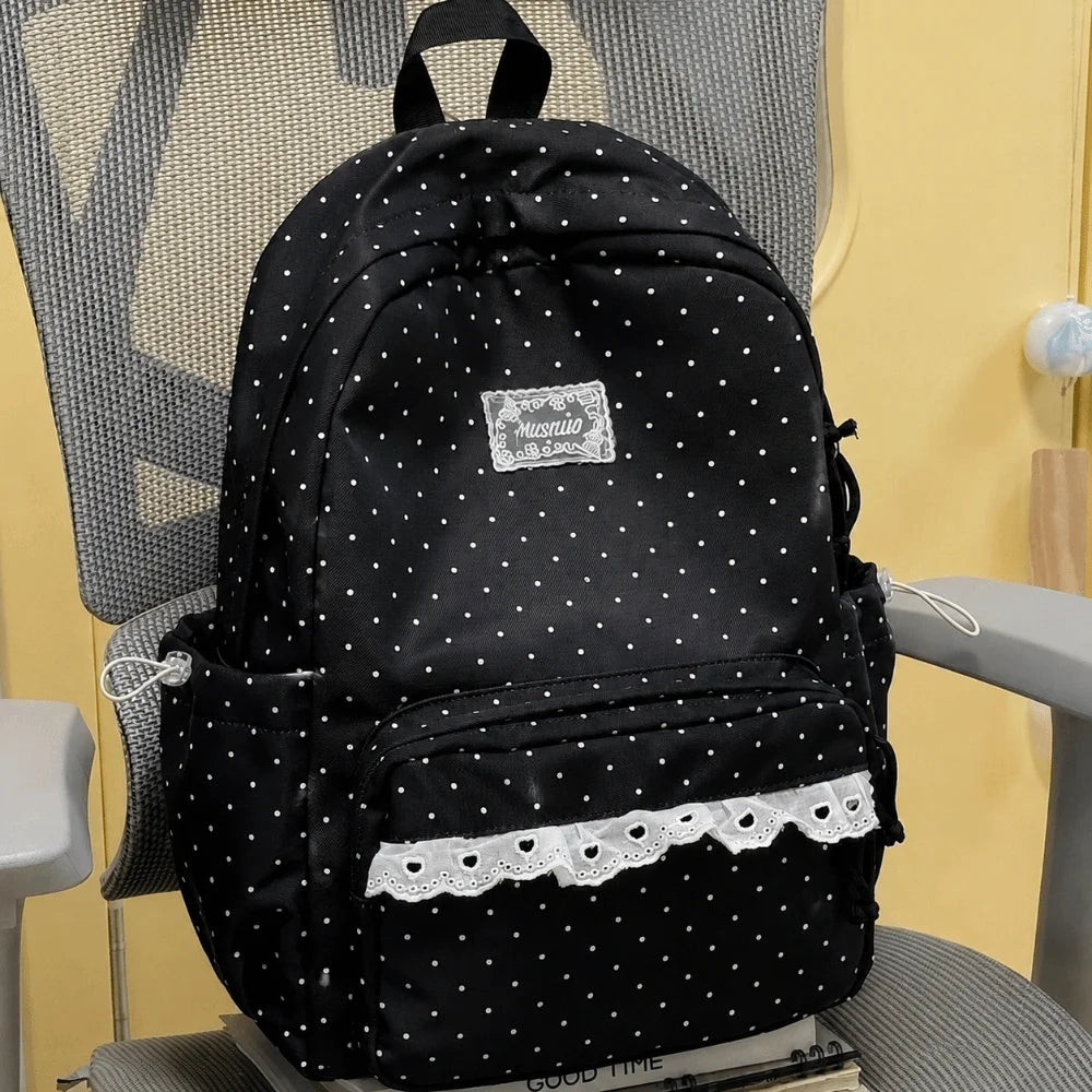 Black polka dot nylon travel backpack with a laptop compartment resting on a gray chair.