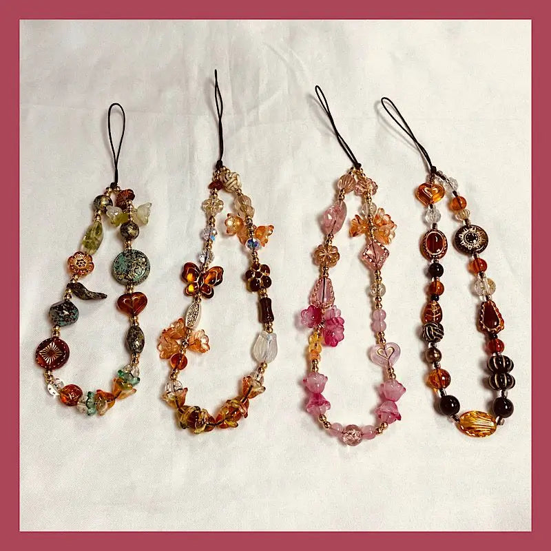 A display of five beaded phone charm straps with anti-lost lanyards featuring various colored stones and beads.