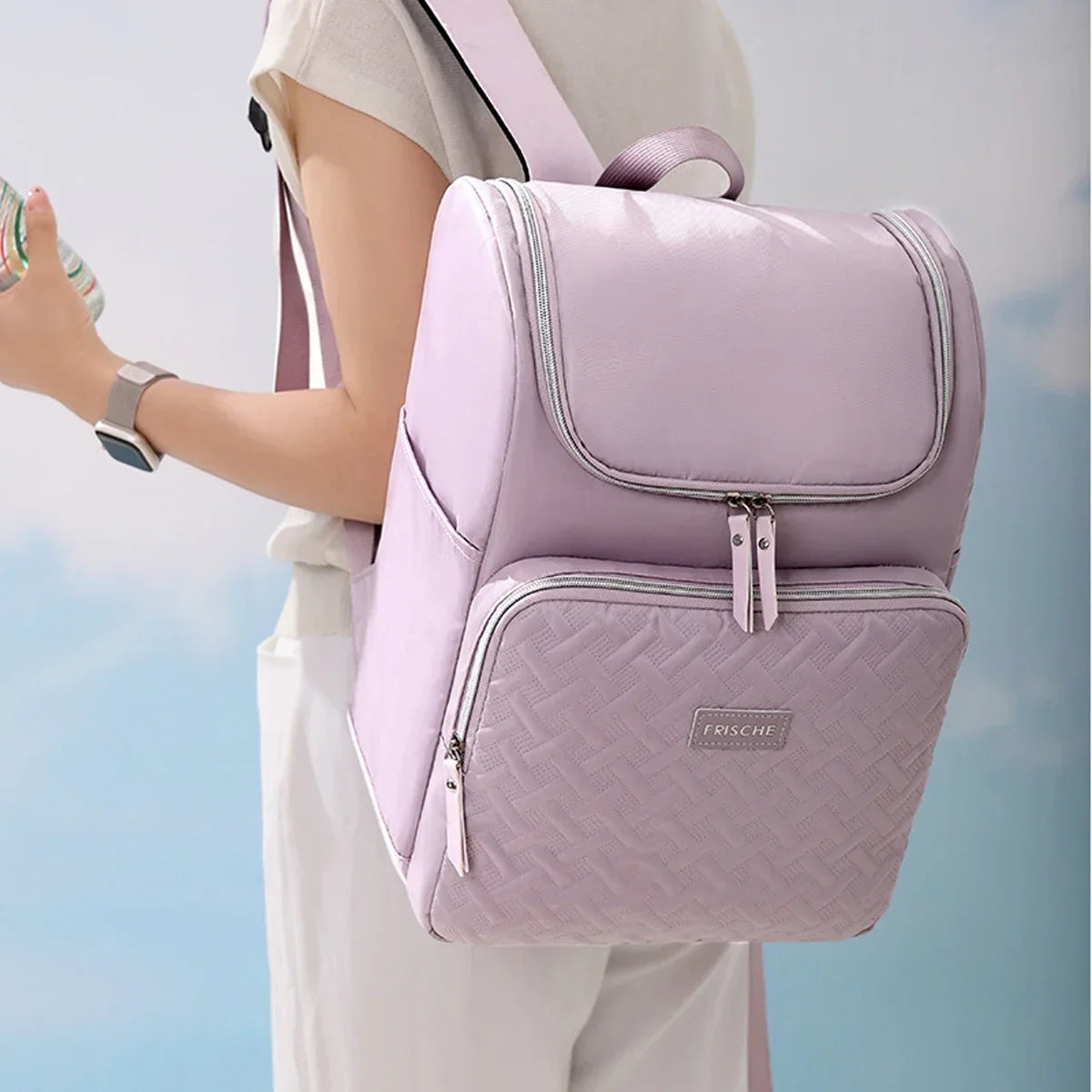 A person is wearing a light pink insulated travel backpack with gray straps and white pants.