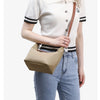 A young woman models a beige nylon dumpling crossbody shoulder bag with black trim and a brown strap.