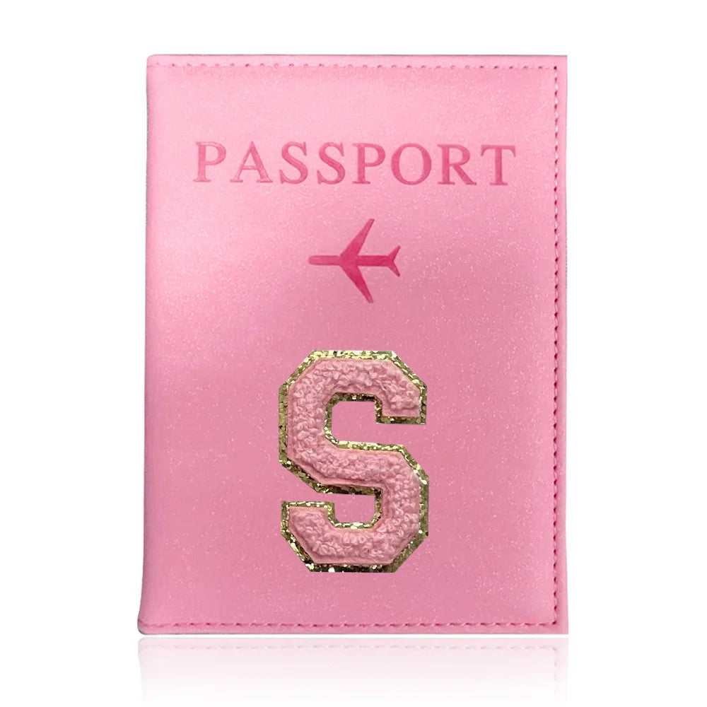 A pink leather passport holder with a gold embossed letter S and a pink airplane symbol.