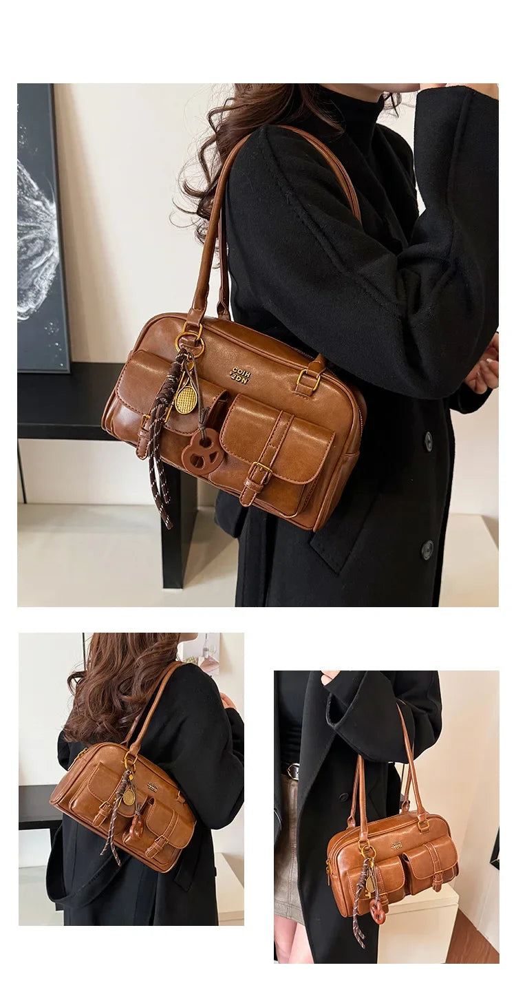 Una mujer sostiene un bolso de hombro de cuero sintético marrón retro con herrajes dorados contra un fondo blanco.