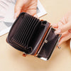 A hand opens a dark brown vintage PU leather compact wallet with a coin pocket.