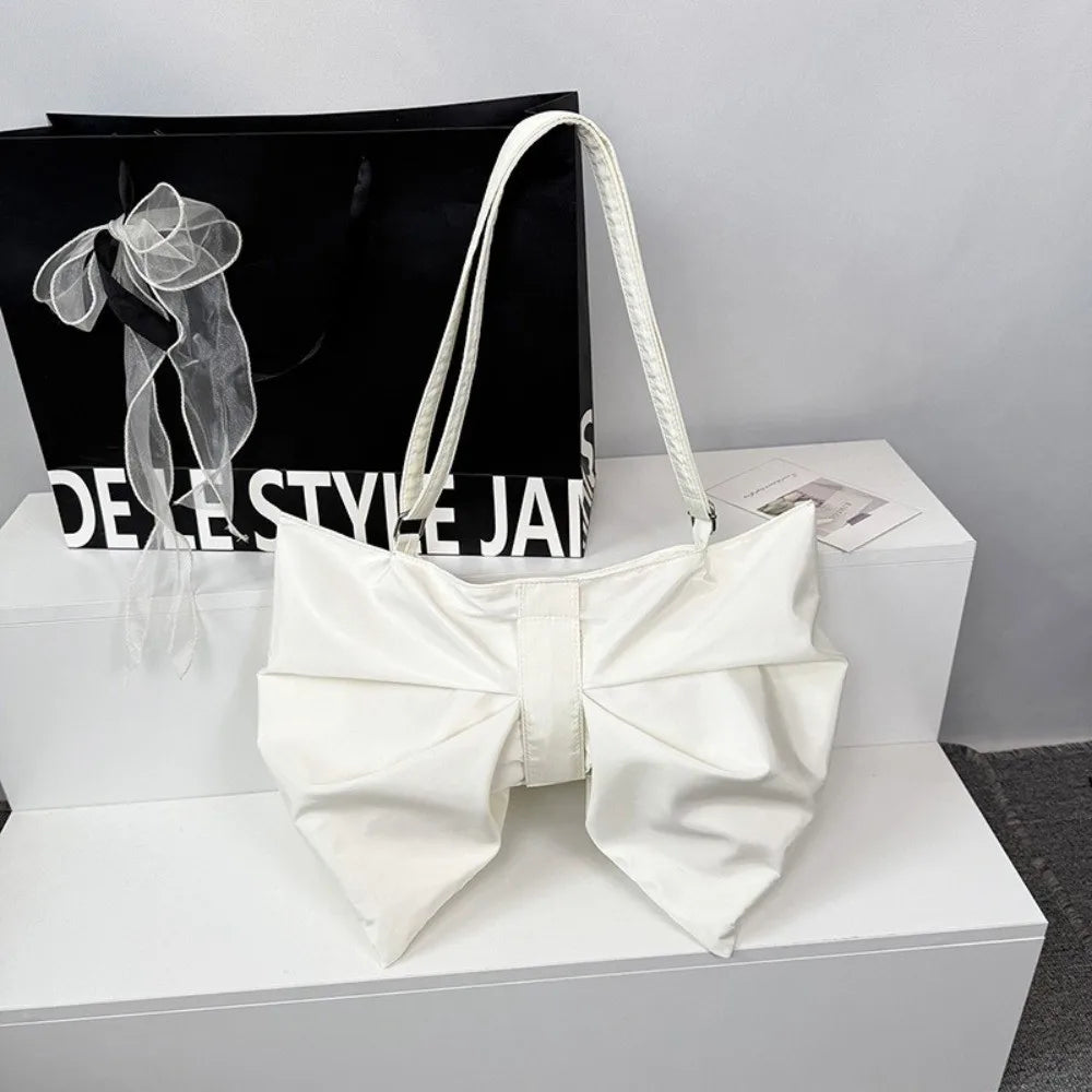 A white elegant pleated bow crossbody tote bag displayed on a white box.