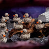 A collection of small, realistic duck figurines with mottled gray and brown feathers resting on dark rocks.