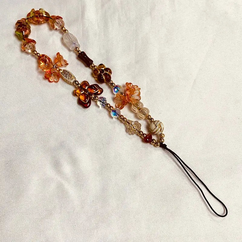 A beaded phone charm strap with anti-lost lanyard featuring amber and clear glass beads.