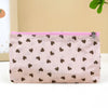 A light pink cosmetic bag with a zipper and a pattern of small brown hearts.