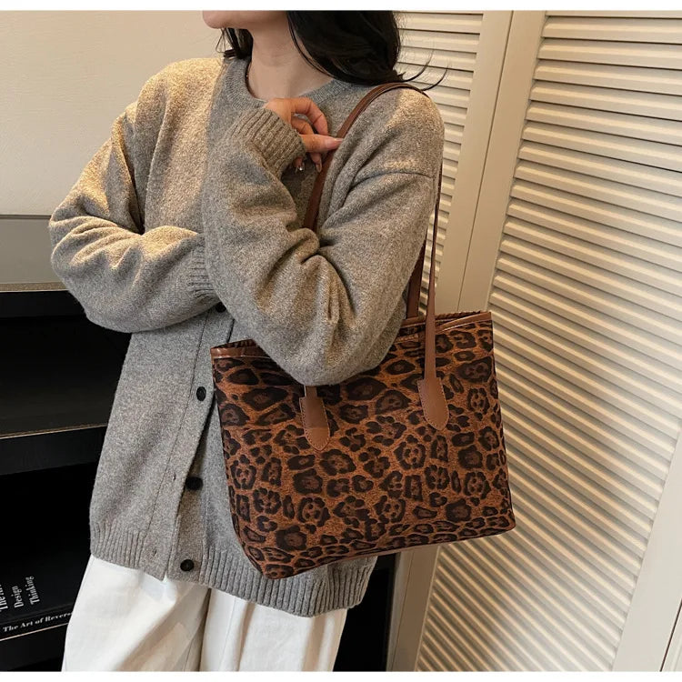 A woman is holding a brown leopard print vintage tote bag and a gray knit cardigan.