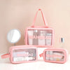 A pink clear waterproof travel toiletry bag with a handle and a matching compact mirror is displayed on a white surface.