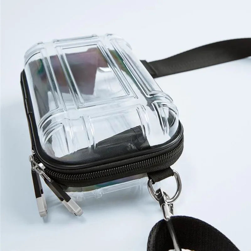 A clear plastic cosmetic bag with a black strap and metal clip is shown against a white background.