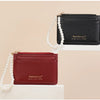 Marron-Leder-Kartenwallet mit goldener Reißverschluss und Perlenkette auf weißem Untergrund