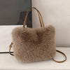 A beige plush faux fur tote bag with a tan leather crossbody strap resting on a white surface.