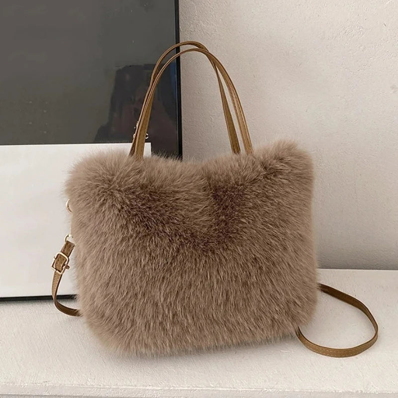 A beige plush faux fur tote bag with a tan leather crossbody strap resting on a white surface.