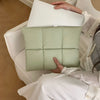 A person is holding a light green quilted laptop sleeve for a MacBook or PC inside a white chair.