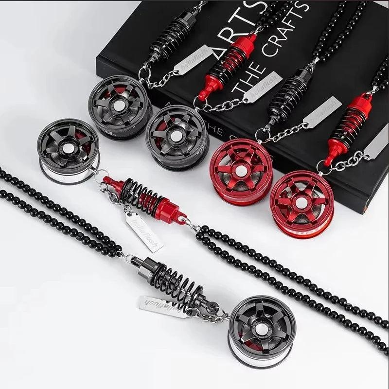 A set of black and red alloy wheel hub brake disc rearview mirror pendants displayed on a black box.