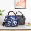 Una bolsa térmica portátil de estampado floral azul junto a una bolsa a rayas blanco y negro sobre una encimera blanca.