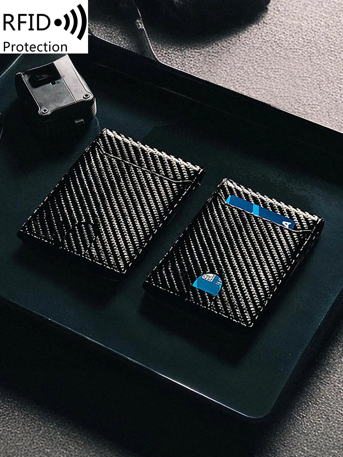 A black slim RFID-blocking front pocket wallet is shown resting on a dark surface next to an RFID protection device.