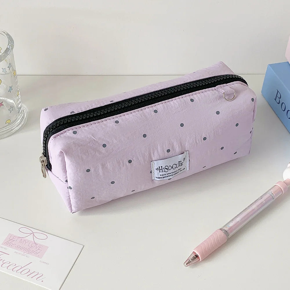 Helles lila Polka-Dot-Stiftcase mit schwarzem Reißverschluss liegt auf weißem Untergrund.