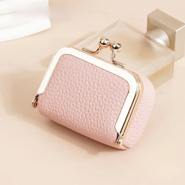 A pink genuine leather coin purse with gold-toned hardware resting on a light colored surface.