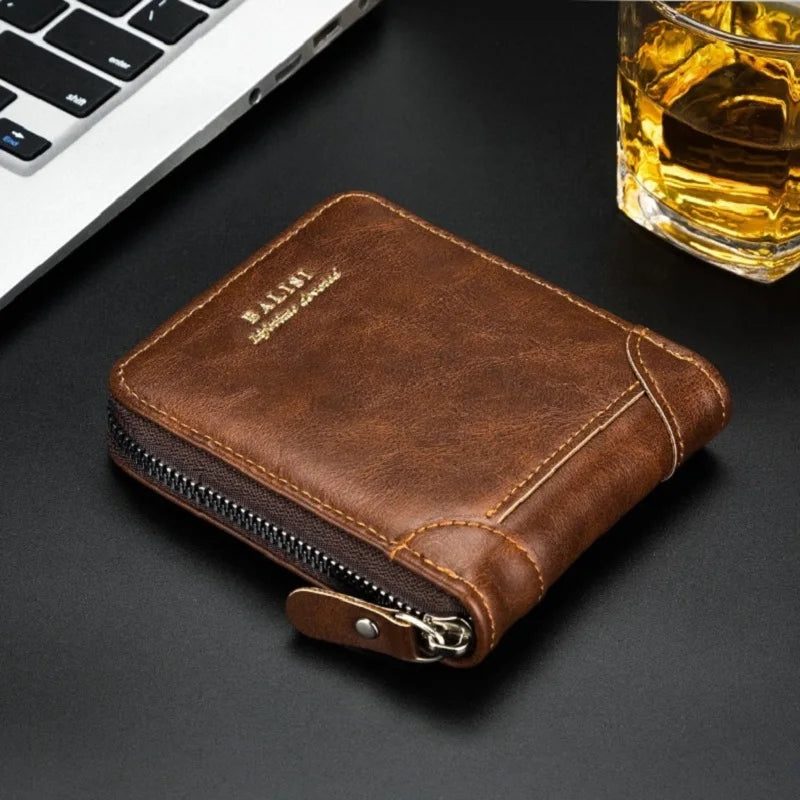 A brown retro PU leather men's wallet with a silver zipper resting on a dark surface next to a laptop and a glass of amber li