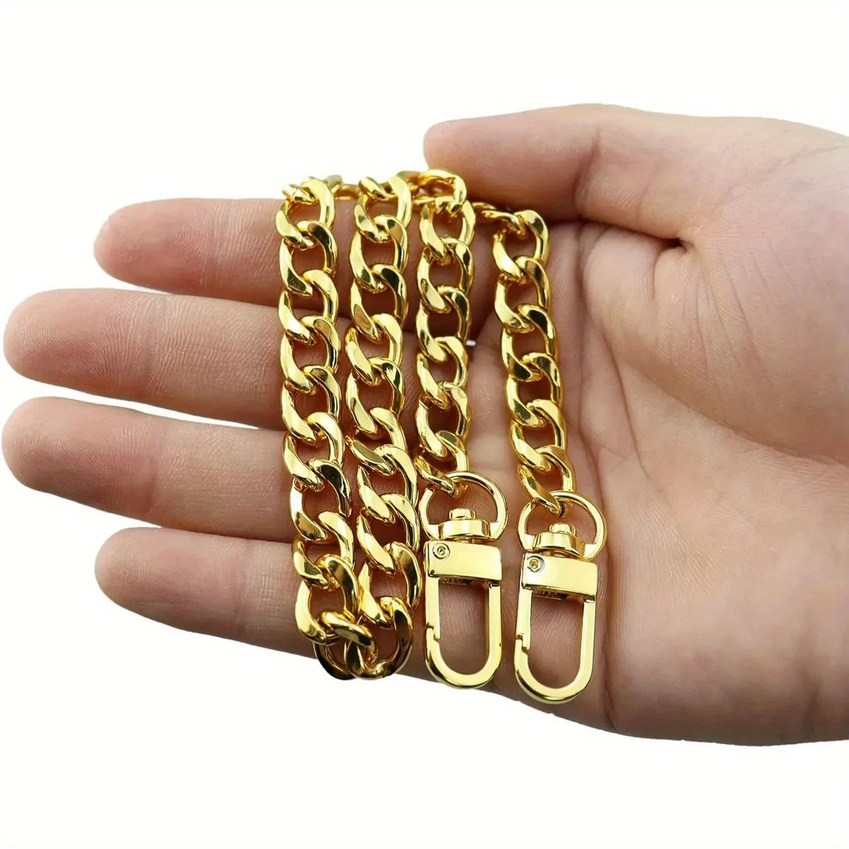 A hand holds several gold-colored metal chain straps for bags and wallets.