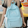 A light blue embroidered backpack worn by a person, featuring white decorative ties.