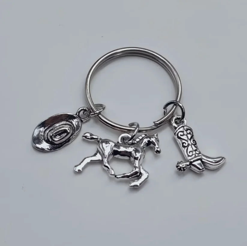 Silver keychain set featuring a cowboy boot, hat, and horseshoe charms.