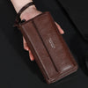 Portefeuille à fermeture éclair en cuir marron pour homme tenu dans une main sur fond noir.