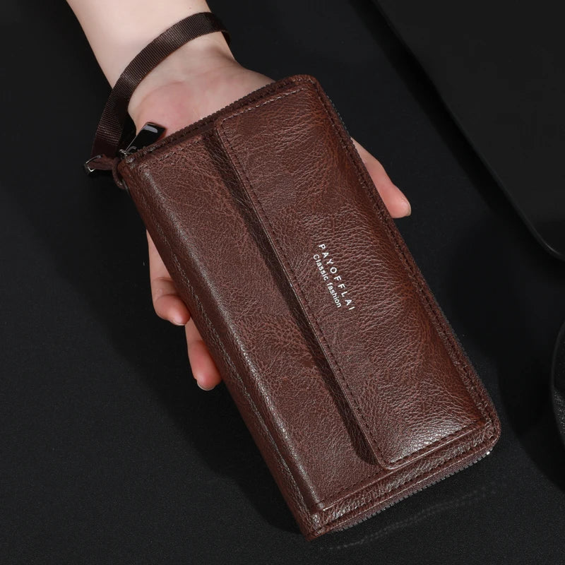 Portefeuille à fermeture éclair en cuir marron pour homme tenu dans une main sur fond noir.