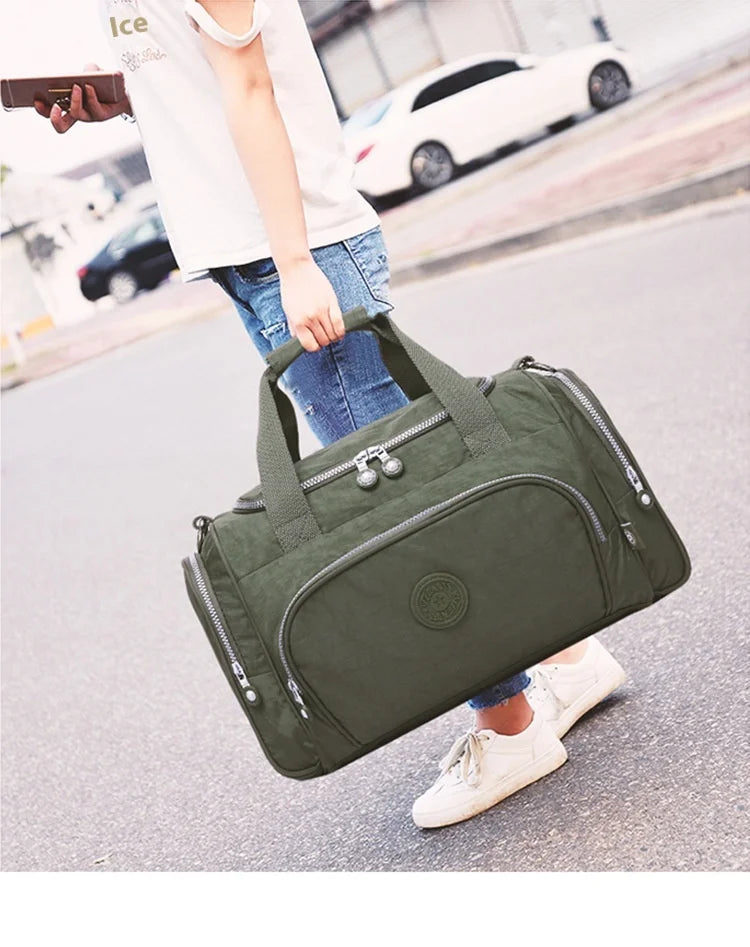 A woman is holding a dark olive green durable nylon travel duffle bag outdoors.