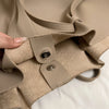 A close-up view of a beige luxury PU leather shoulder tote bag showing the strap and a metal closure.