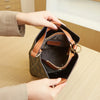 A hand is opening a brown Western floral bucket bag with a leather strap, showing the interior lining.