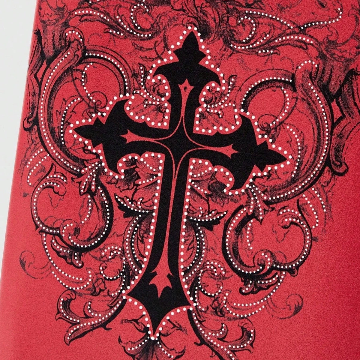 A close-up of a red fabric featuring a black gothic cross pattern outlined with white dots.