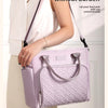 A woman holds a light purple quilted insulated lunch bag against a white background.