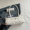 Weiße Leder-Schultertasche mit schwarzen Polka Dots und weißem Stoffgriff auf einer Jeansjacke.
