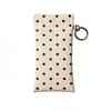 A beige polka dot eyeglass pouch with a silver keychain attached.