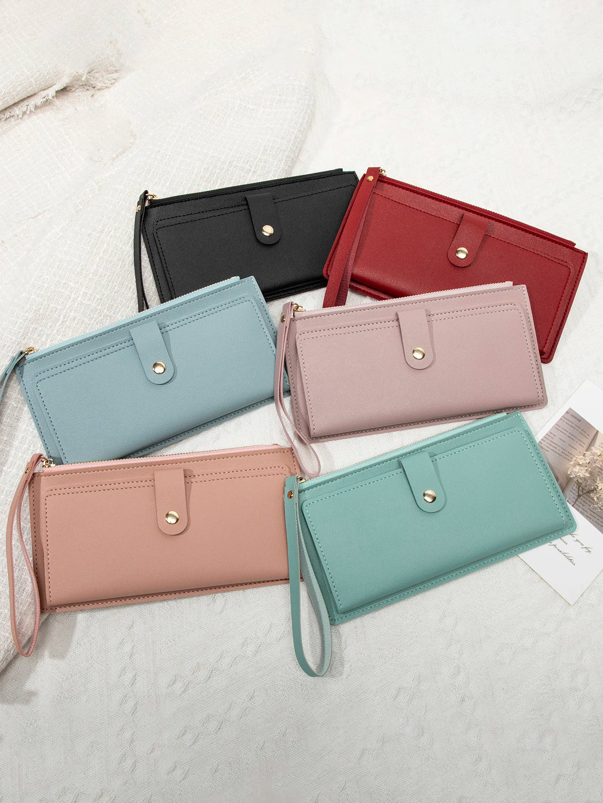 A collection of elegant PU leather coin purses and card holders in black, red, pink, and mint green colors arranged on a whit