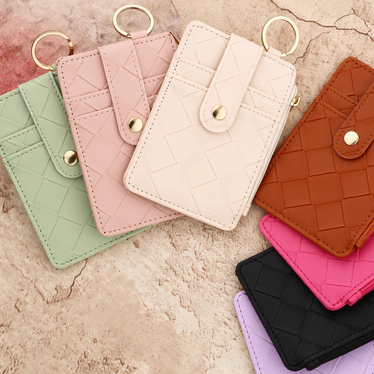 A collection of five pink, green, beige, and brown PU leather card holder wallets with gold rings.