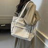 A light beige corduroy shoulder bag with vertical ribbing and fringed details is carried by a person.