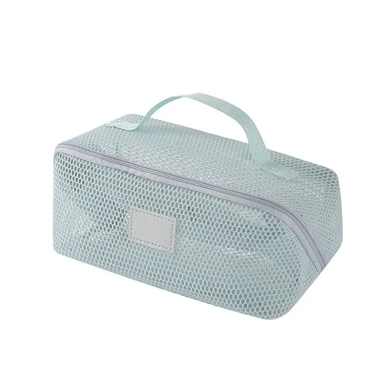 A light mint green mesh pouch with a handle used for organizing cosmetics and toiletries.