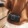 A brown jacket is worn by a person, featuring a black PU leather crossbody bag with a rhinestone buckle.