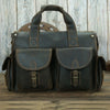 A dark brown genuine cowhide leather briefcase with two flap pockets and leather handles resting on a wooden surface.