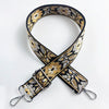 A close-up of a black and gold patterned fabric strap for an adjustable crossbody bag.