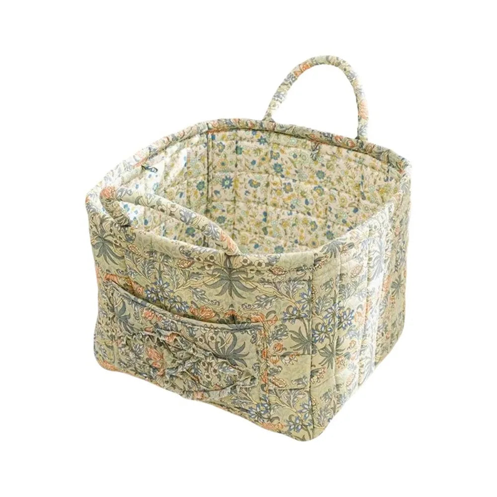 A quilted fabric storage basket with light floral pattern and carry handles.